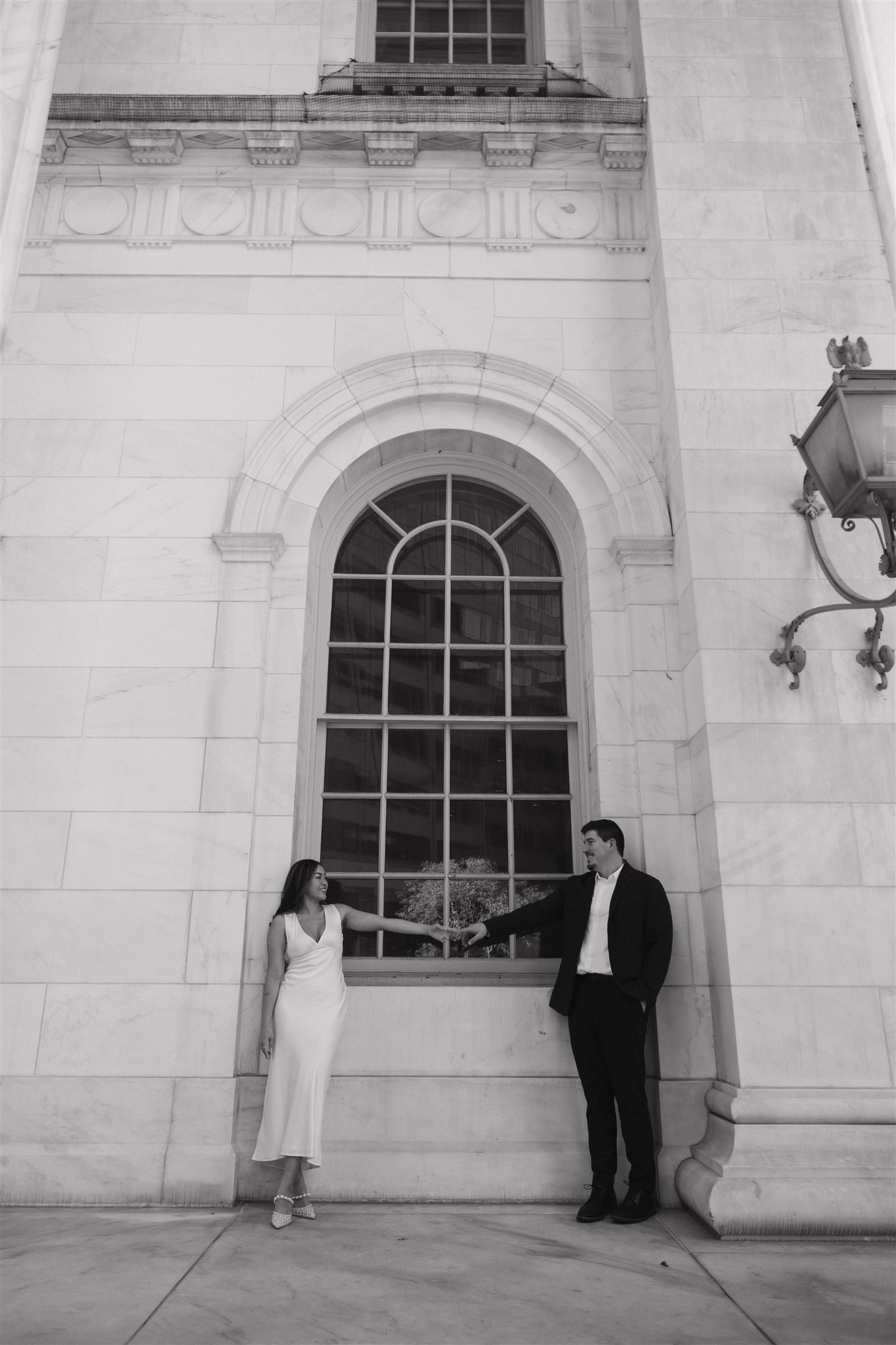 a man and woman touching hands in front of the courthouse window 