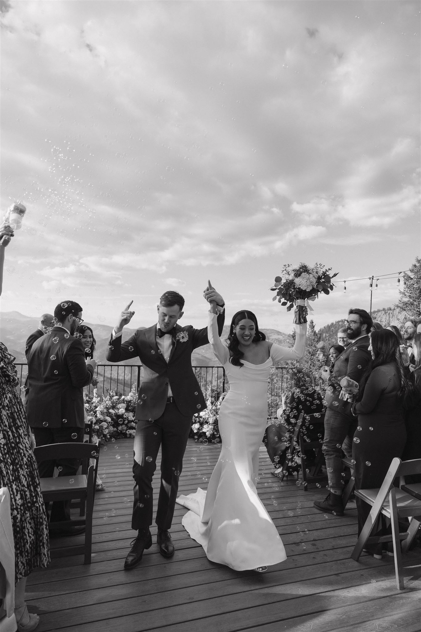 candid photo of bride and groom walking down the aisle with bubbles 