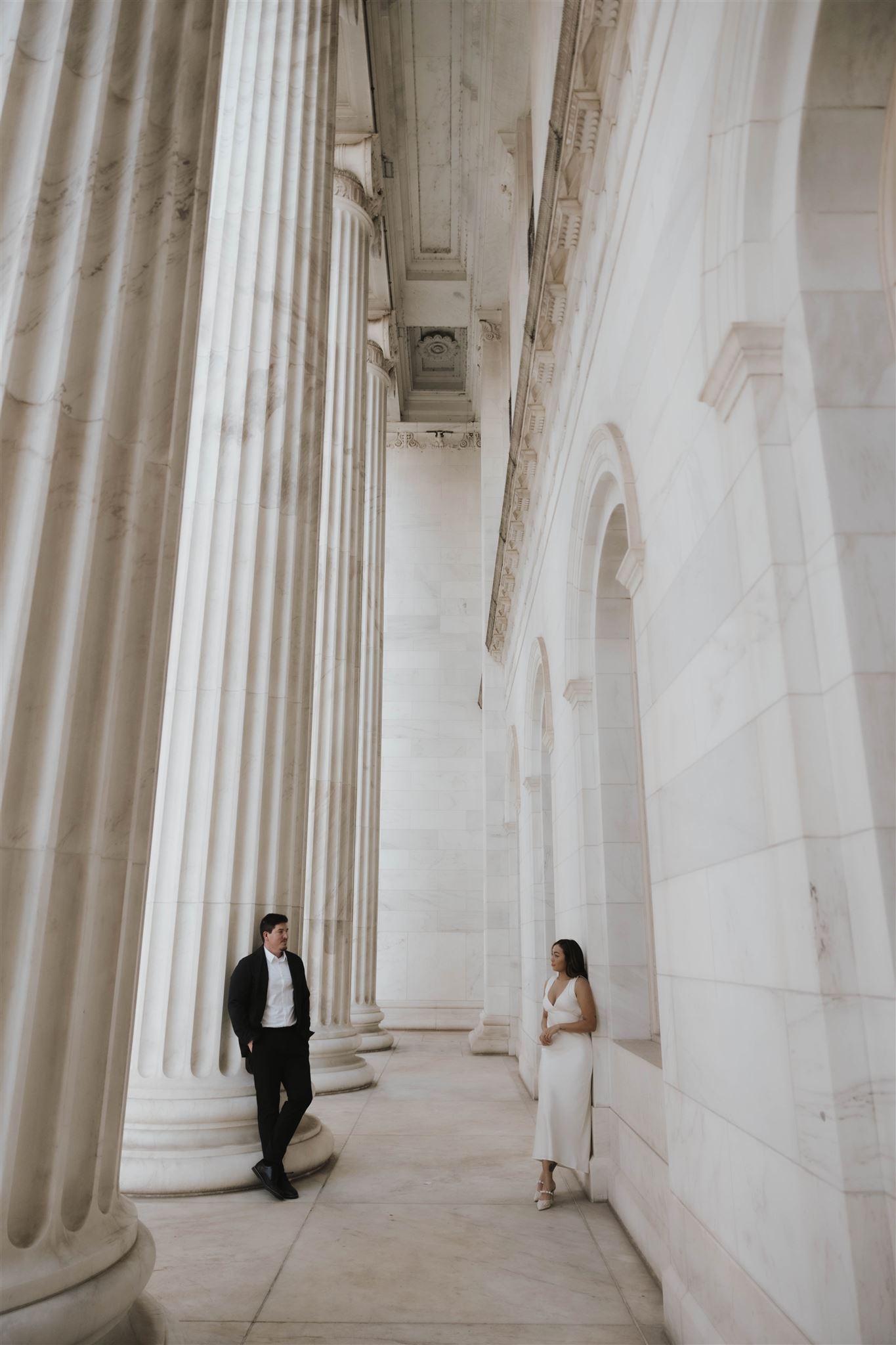 a newly engaged couple standing against the aesthetic courthouse during their Elegant Engagement Photos