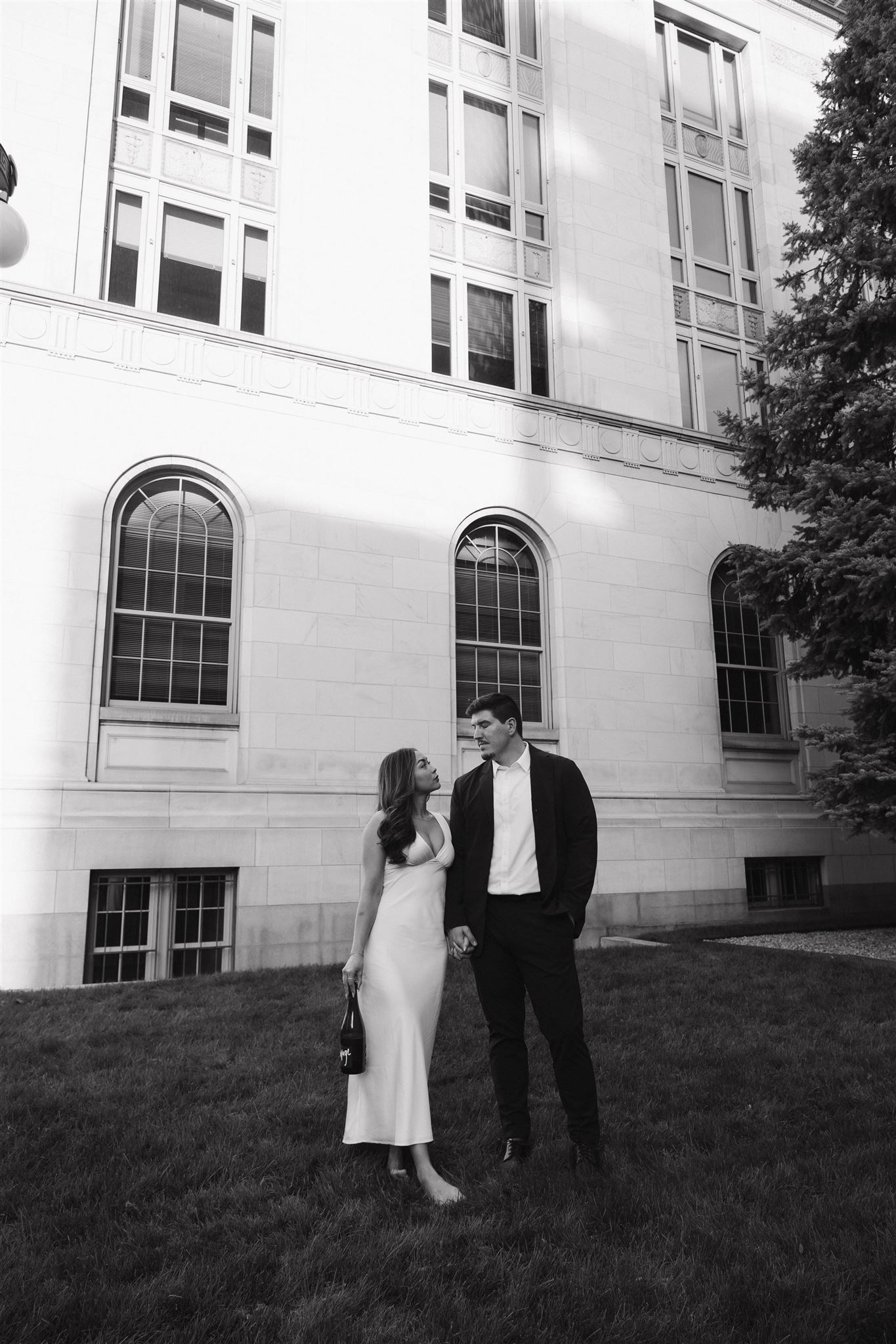 newly engaged couple looking at each other while standing in the grass for their Elegant Engagement Photos