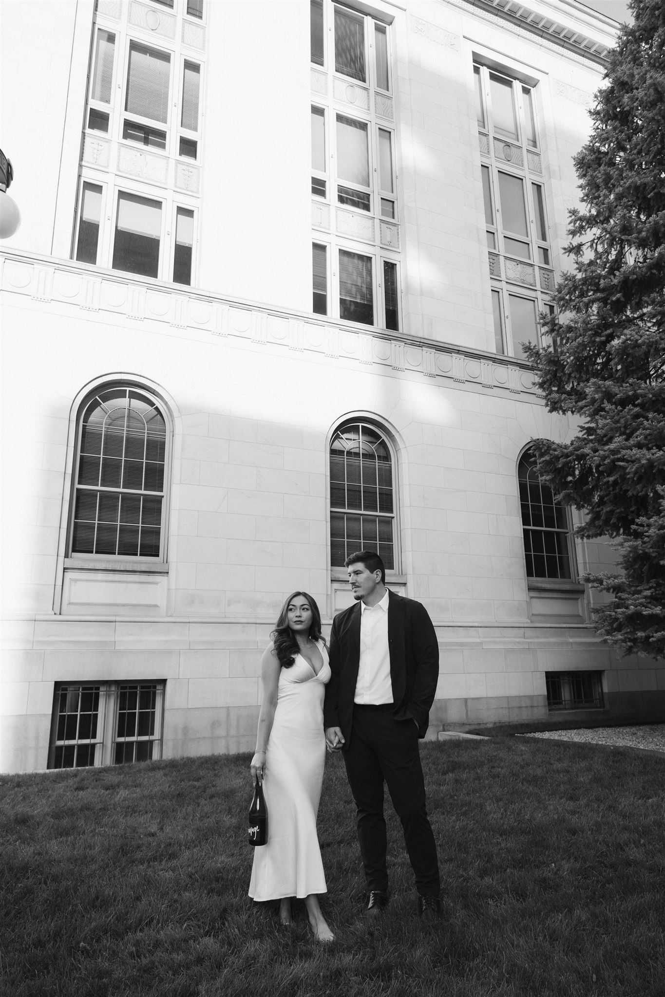 an editorial engagement photo of a couple standing together and looking off into the distance 