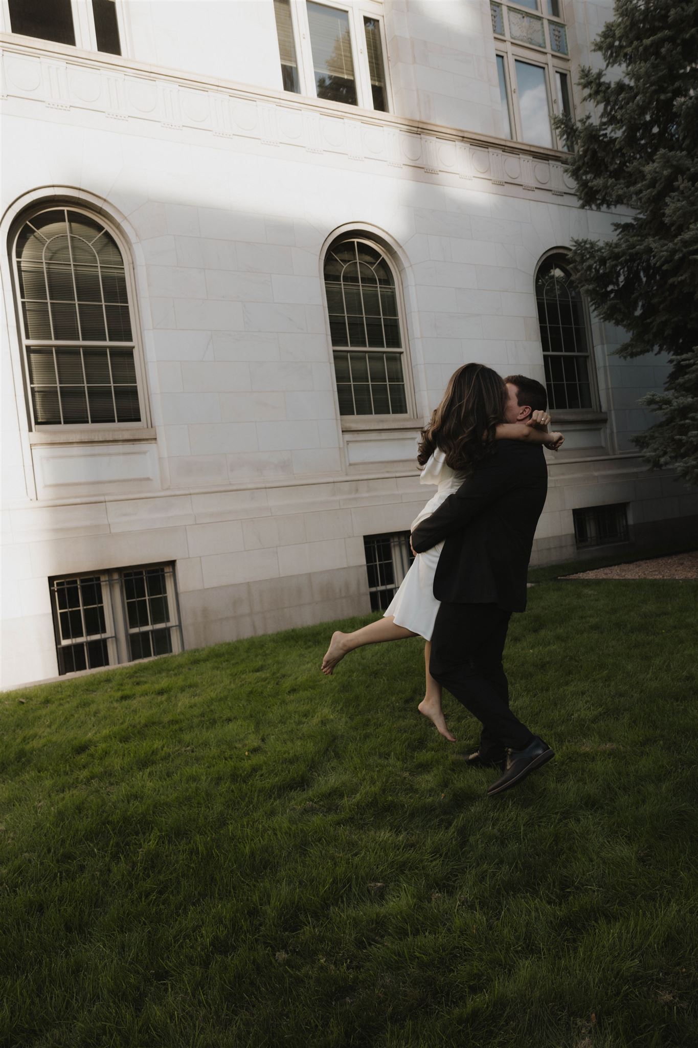 a man holding a woman as they kiss in the grass during their Elegant Engagement Photos