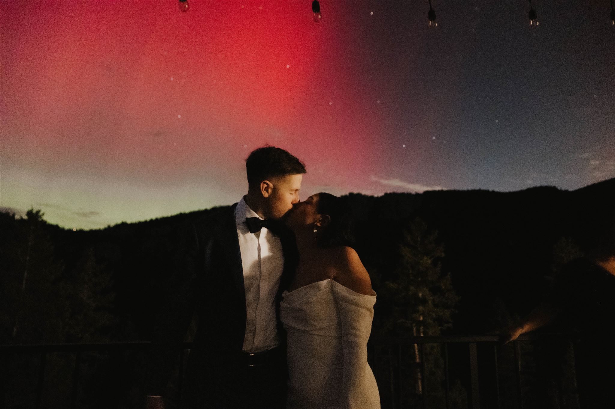 bride and groom kissing with the northern lights behind them 