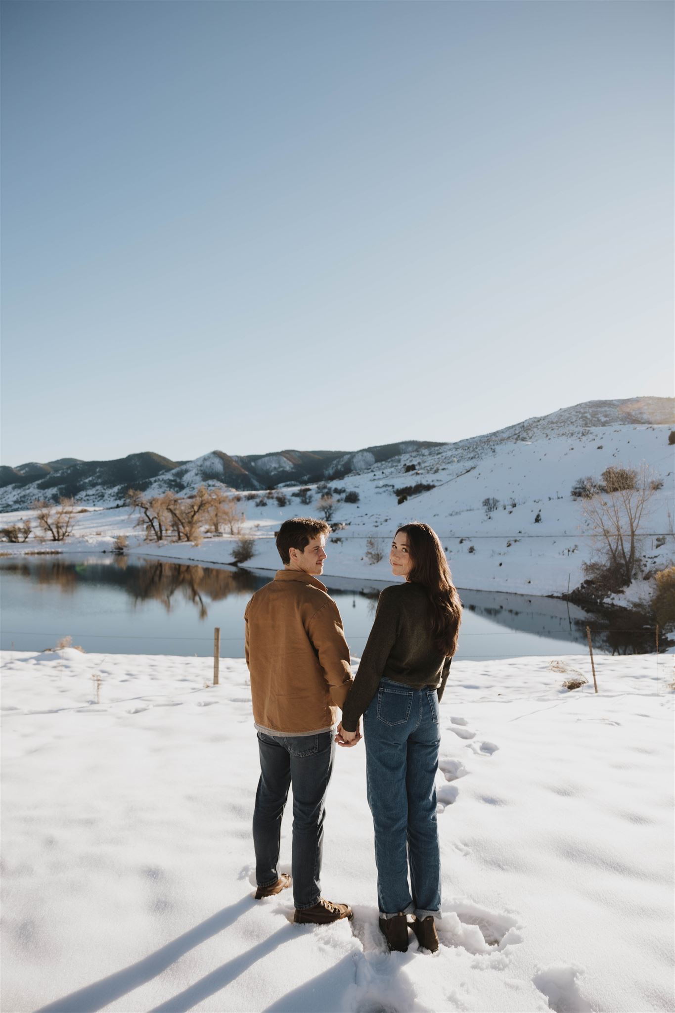 newly engaged couple holding hands and looking back at the camera 