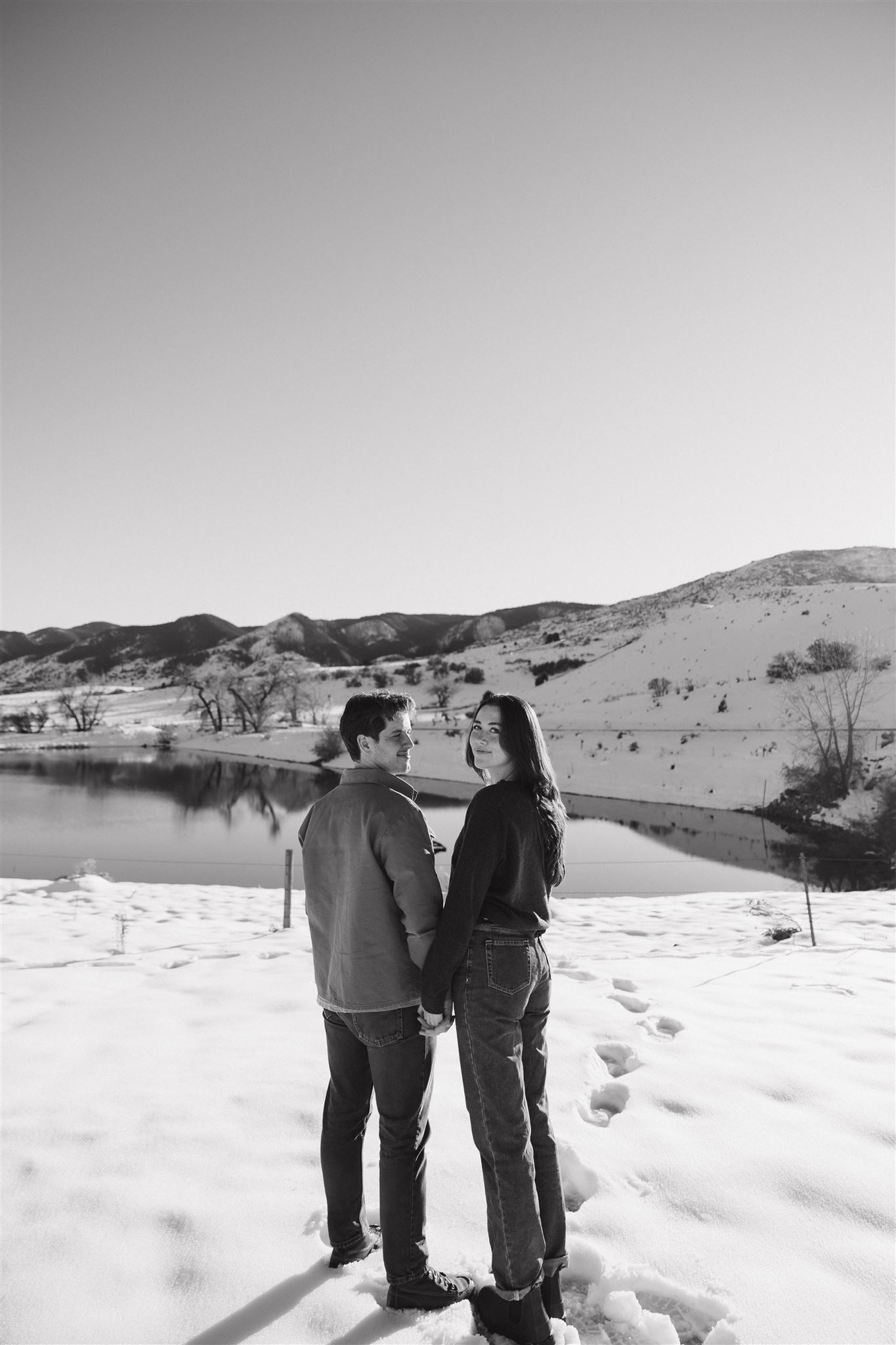 newly engaged couple standing in the snow for their Snowy Engagement Photos