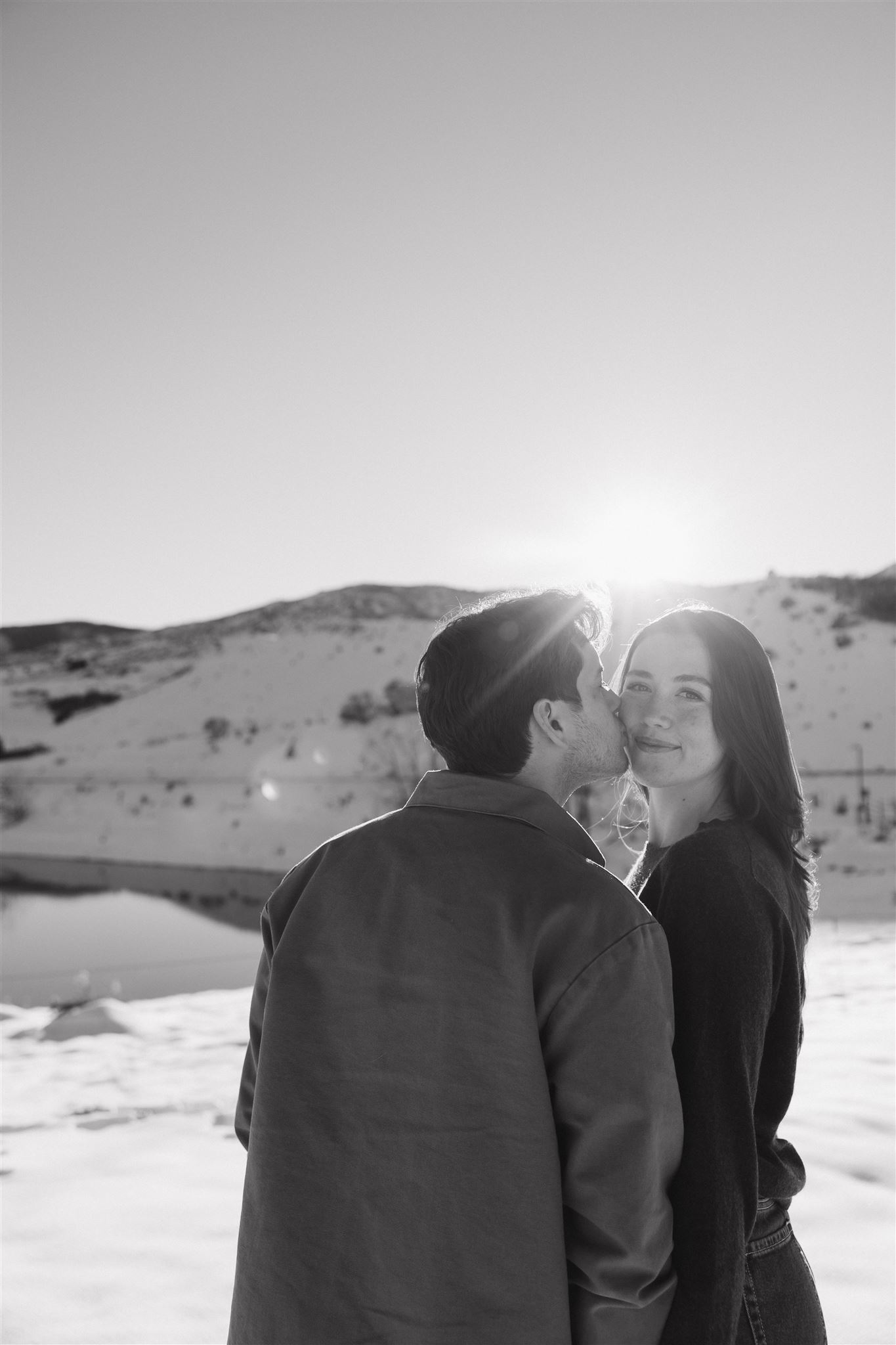 a man kissing a woman's cheek during Snowy Engagement Photos in CO