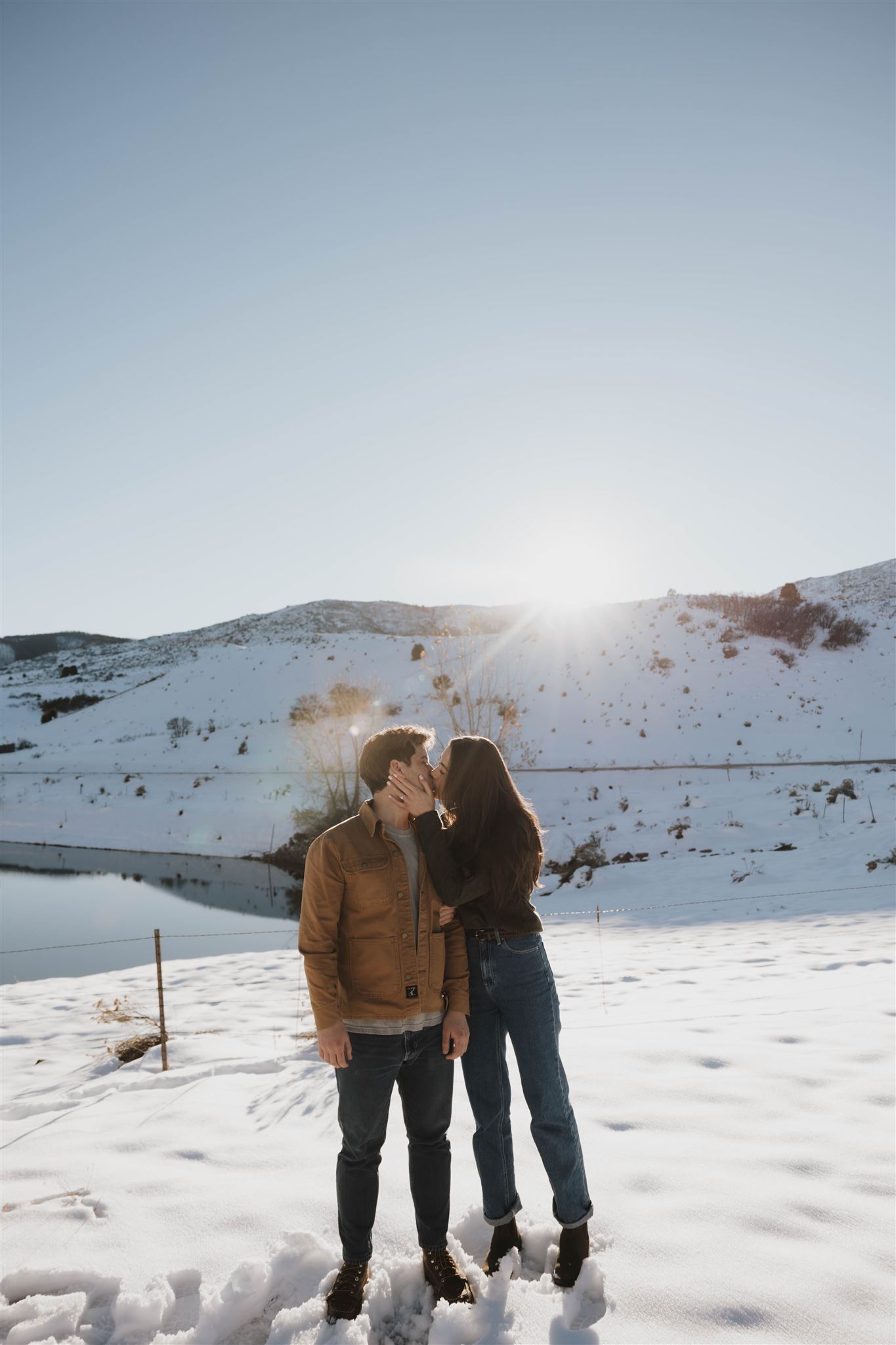 a man and woman kissing during their Snowy Engagement Photos