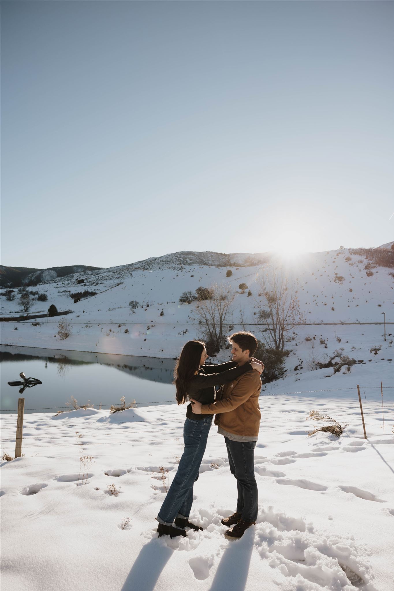 a man and woman holding and looking at each other during their Snowy Engagement Photos