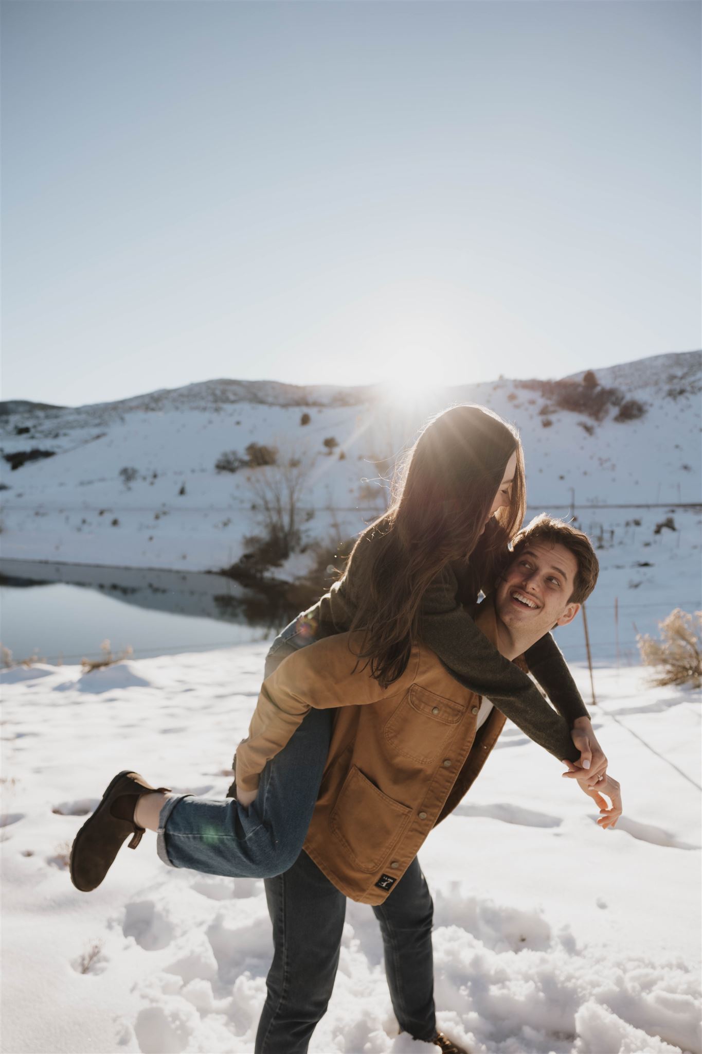 a woman on a man's back during Snowy Engagement Photos