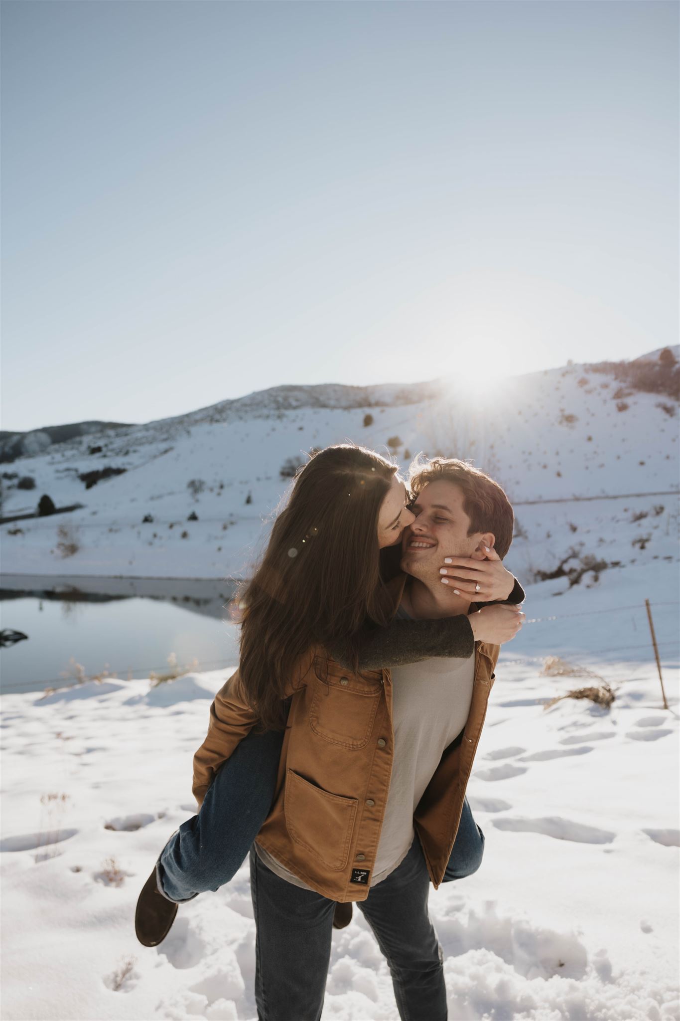 newly engaged couple having fun together outside in the snow during their Snowy Engagement Photos