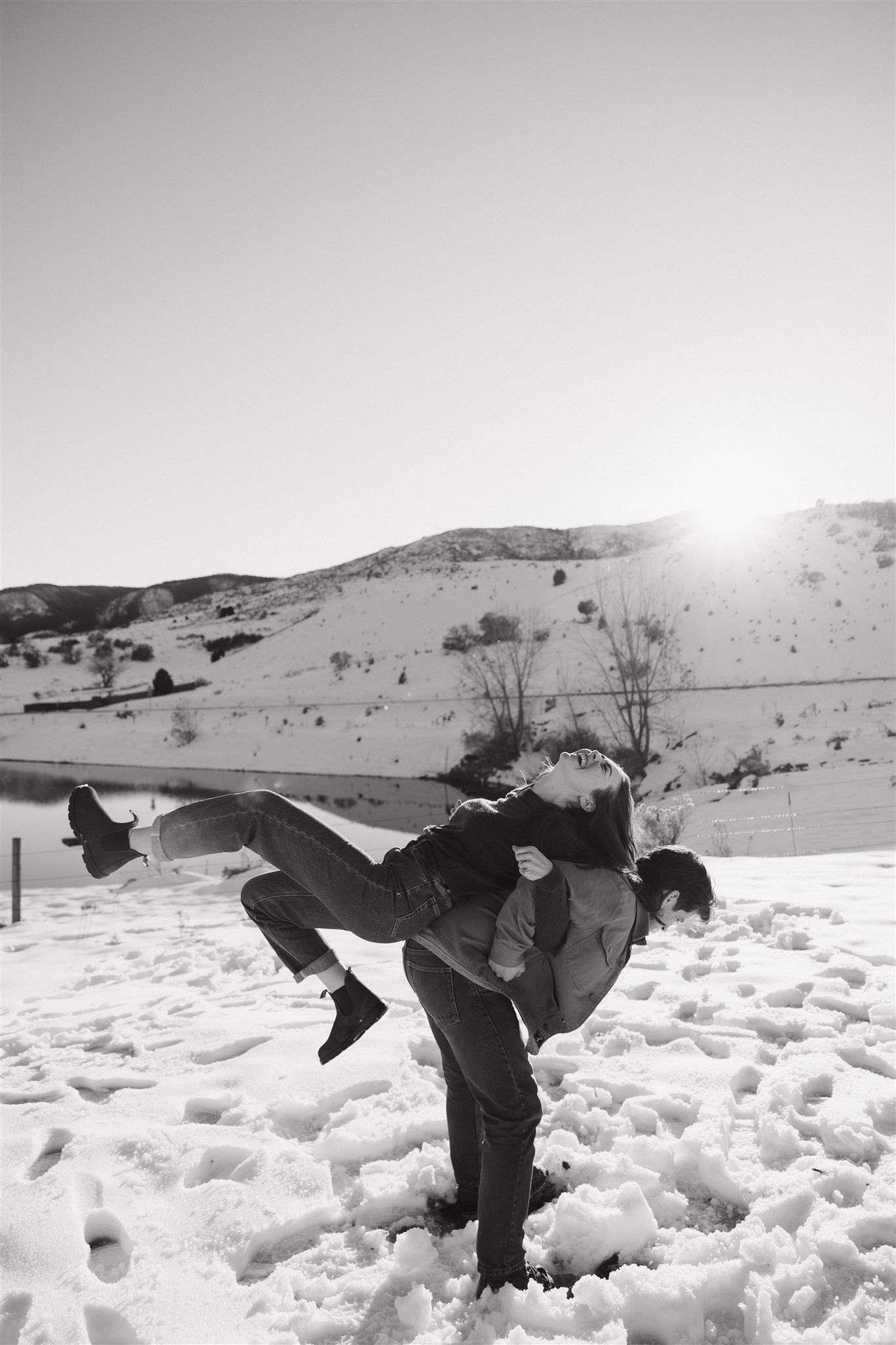 a man and woman having fun together during their Snowy Engagement Photos