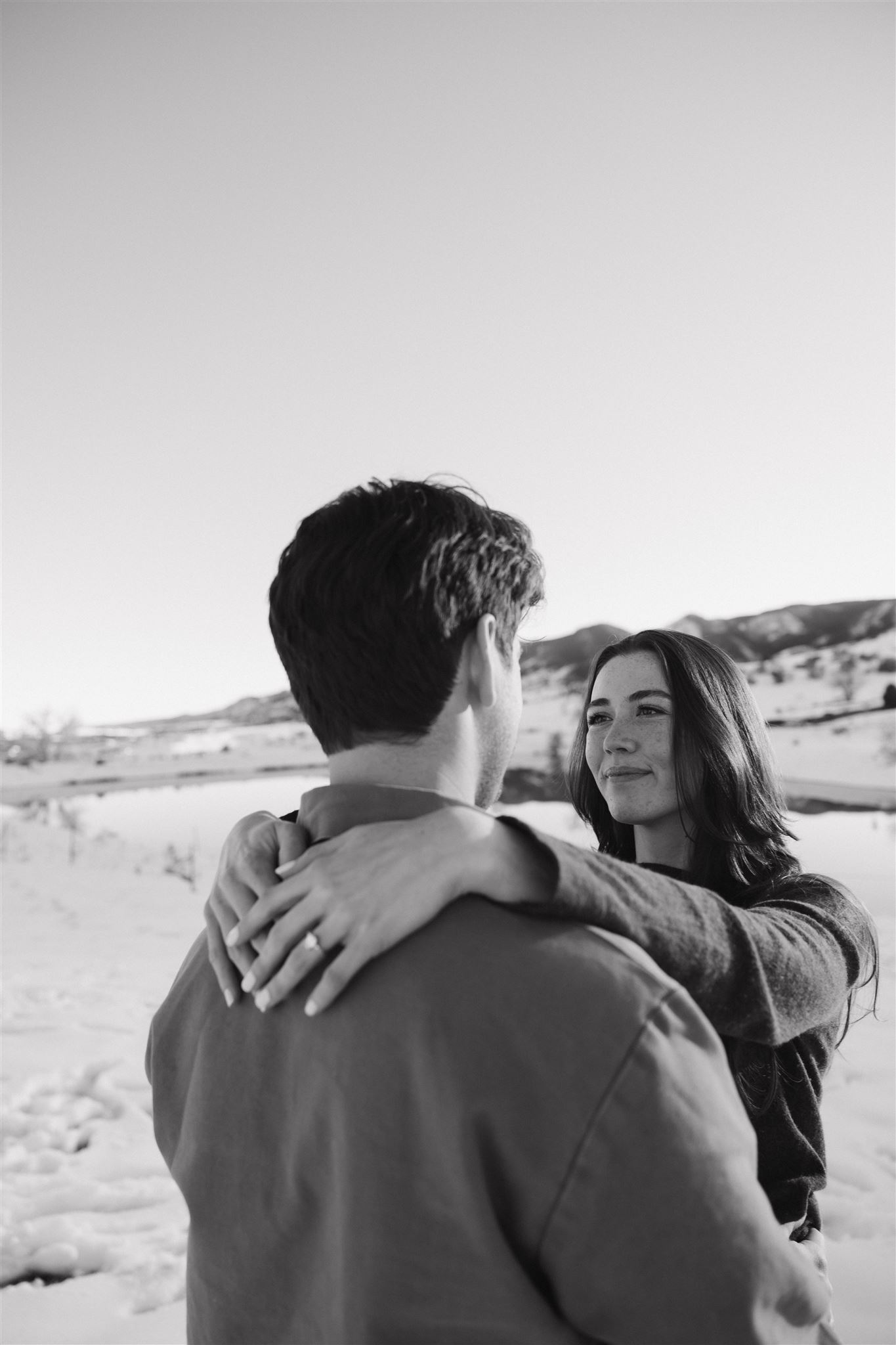 a woman looking at her man during their Snowy Engagement Photos