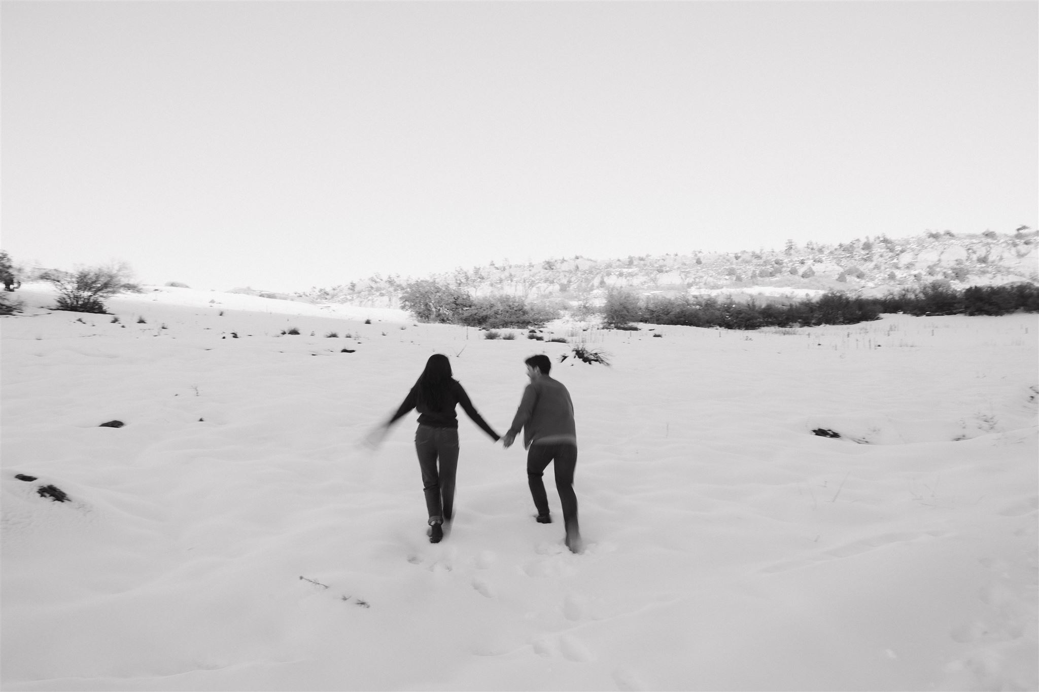 a couple running off into the snow together 