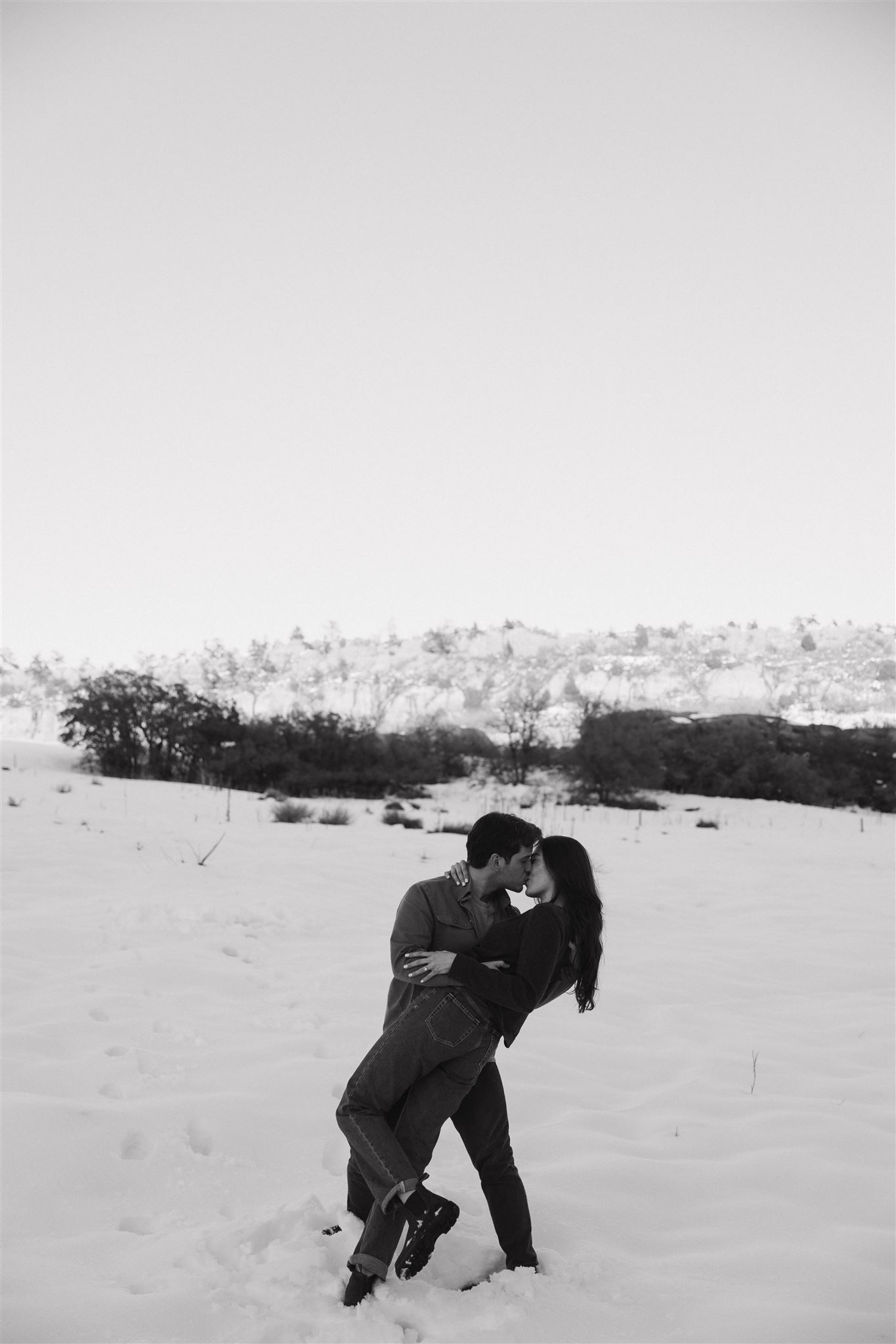 a man dipping a woman during their Snowy Engagement Photos