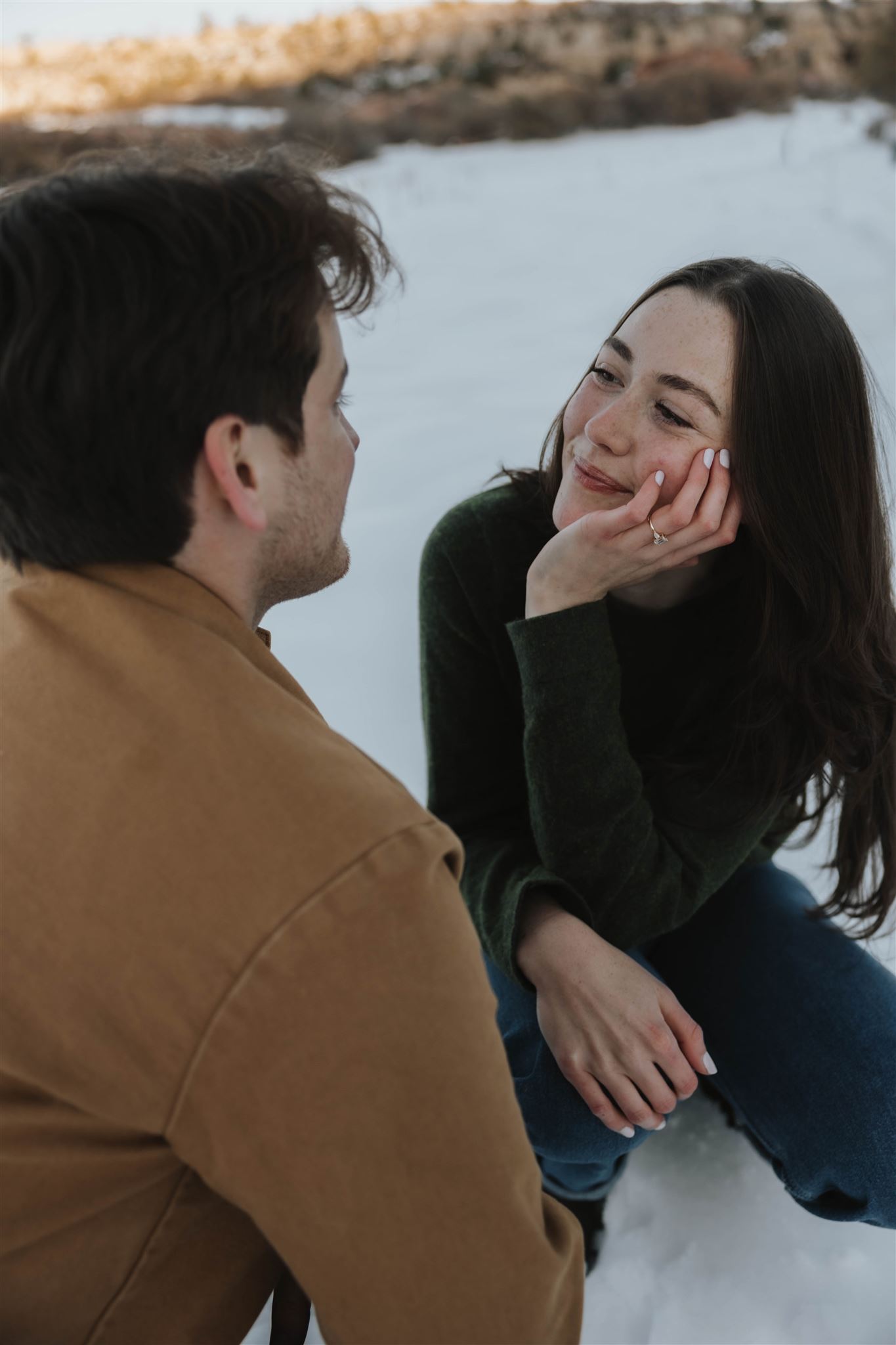 a woman looking at a man with love in her eyes during Snowy Engagement Photos