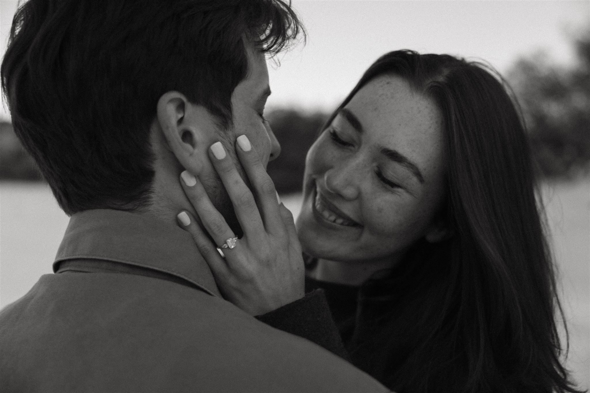 a man and woman close up of them smiling and holding each other's face 