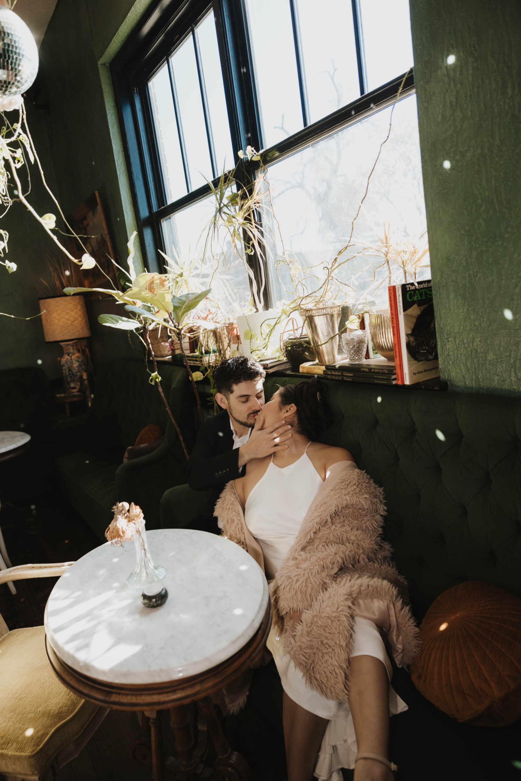 man and woman sitting in a booth kissing during their engagement photos 