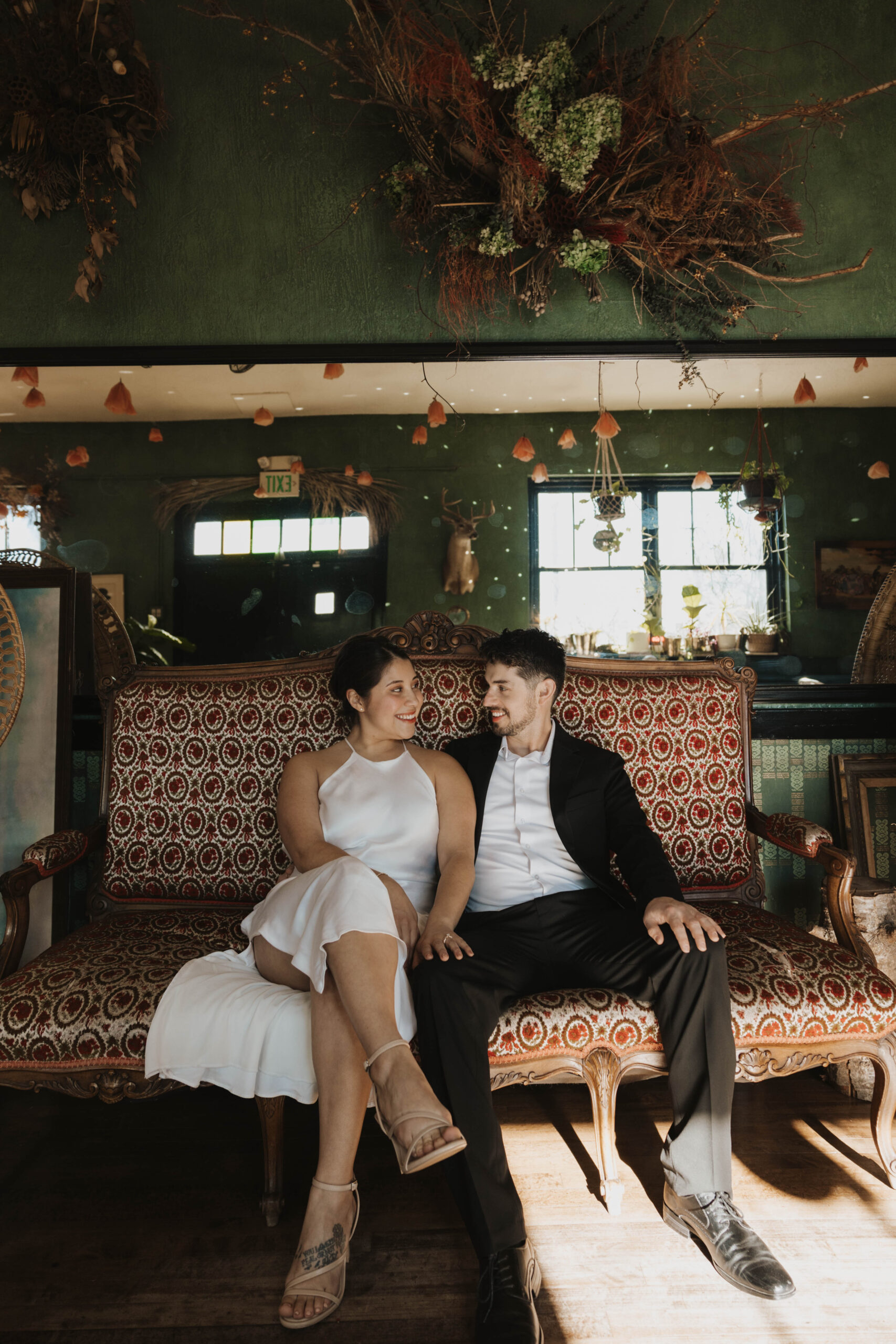 engaged couple sitting on a couch in a bar for their engagement photos 