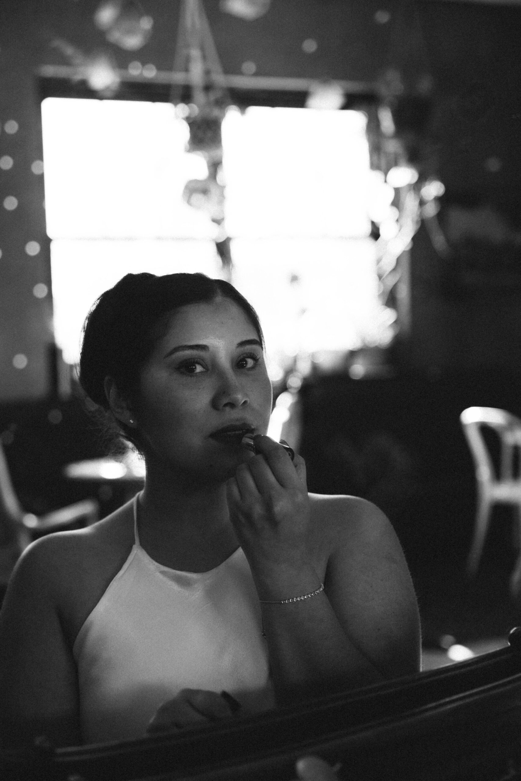 a woman looking into the mirror while she puts on lipstick during her engagement session