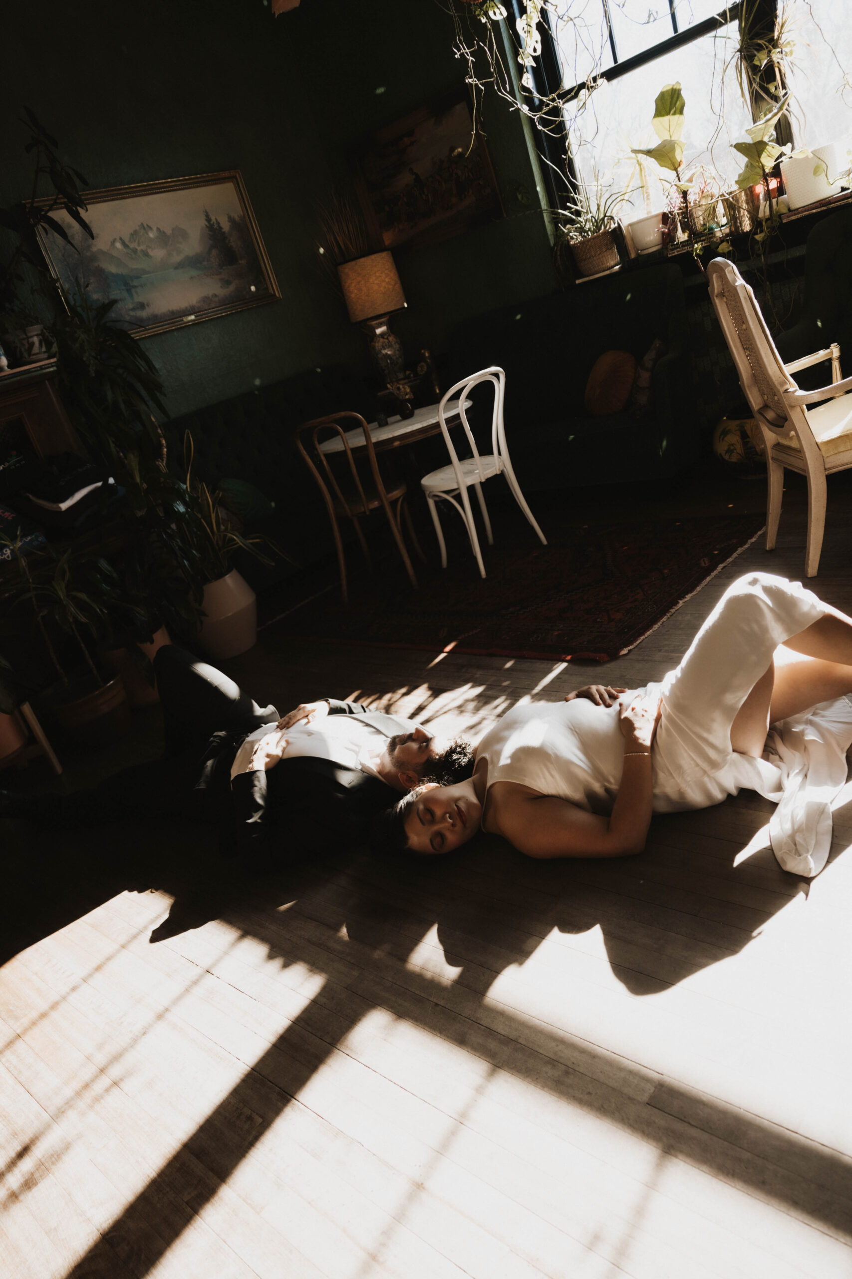 newly engaged couple laying on the floor of a bar with light and shadows cast on them 