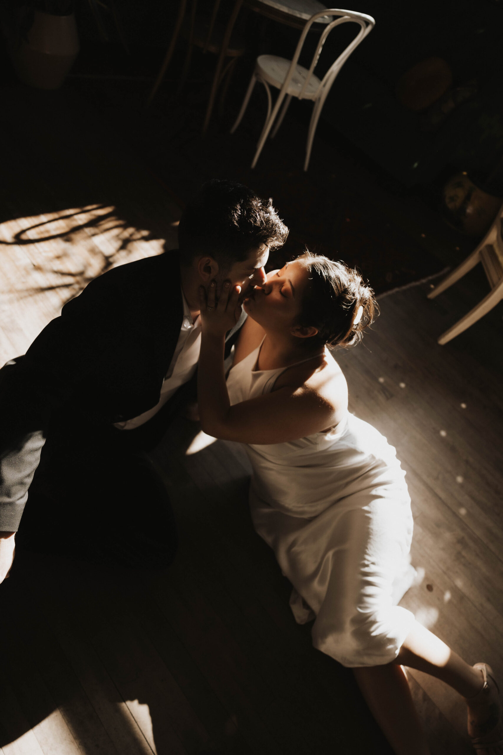 a couple sitting on the floor with shadows and light on them as they kiss