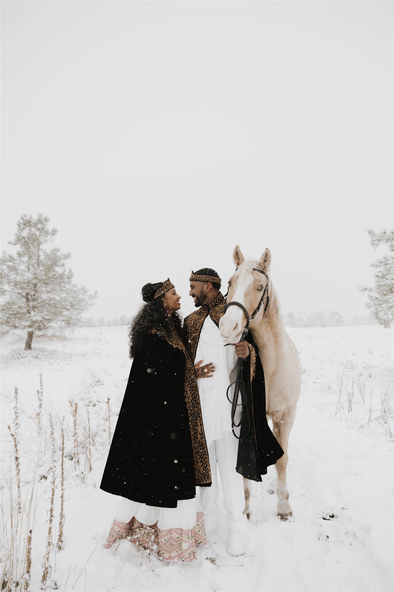 newly engaged couple with a horse as the magical snow falls down on them 