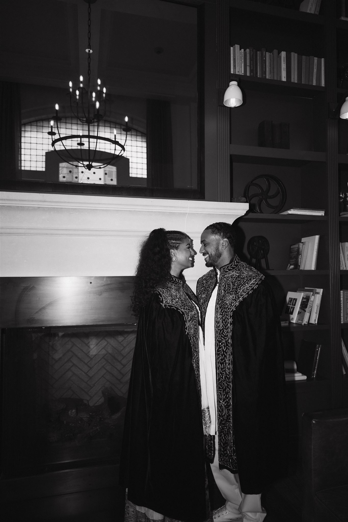 newly engaged couple smiling at each other in a romantic library 