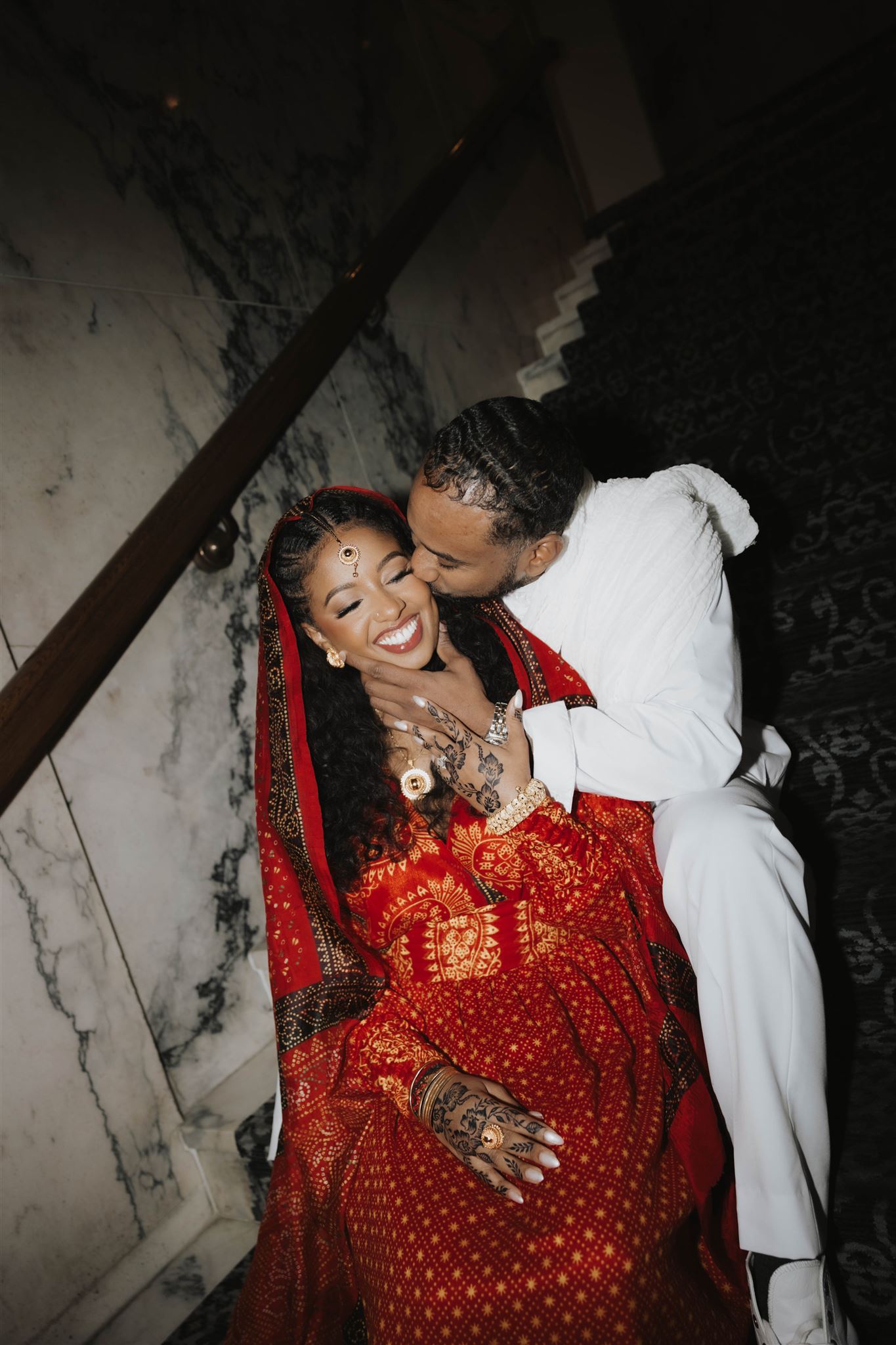 newly engaged couple sitting on the steps in traditional attire during their unique engagement photos